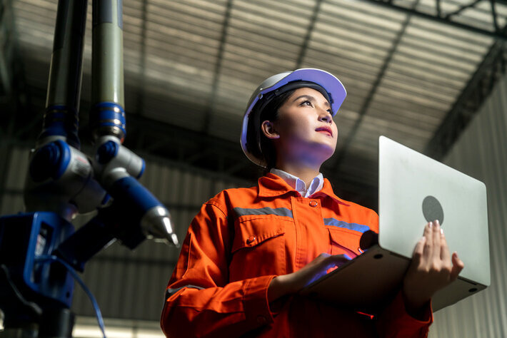 Engineer specialist asian female and technician maintenance inspect relay robot arm system with laptop to control quality operate process work heavy industry 40 manufacturing smart factory