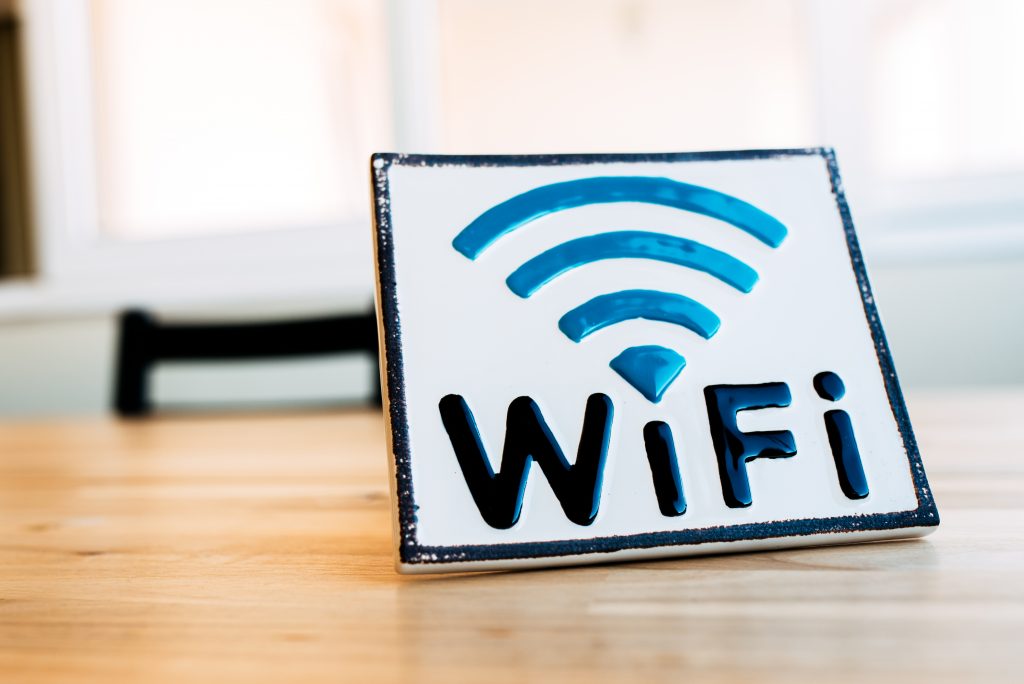 White square badge with sign of wireless connection for gadgets on wooden surface